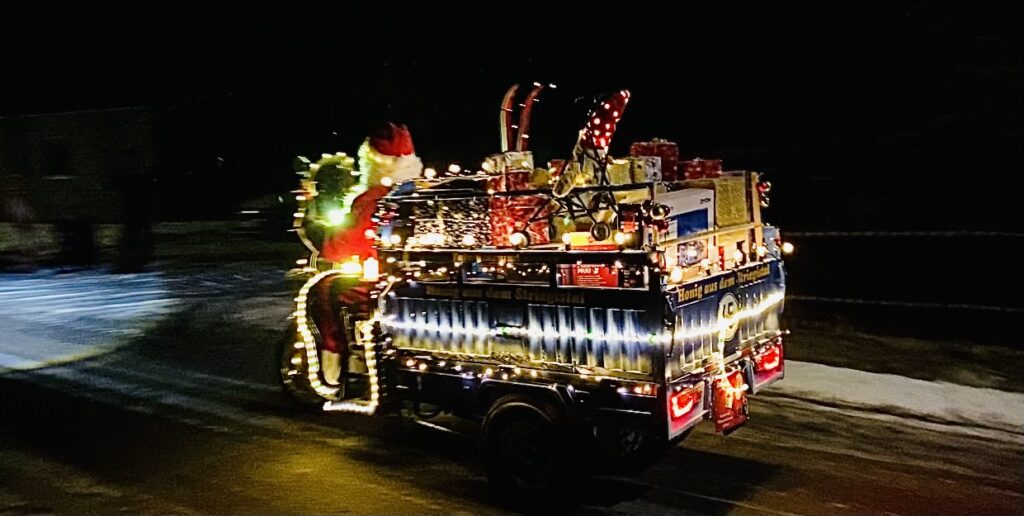 Weihnachtlich geschmückter Cargo Runner fährt nachts auf einer Straße im Winter