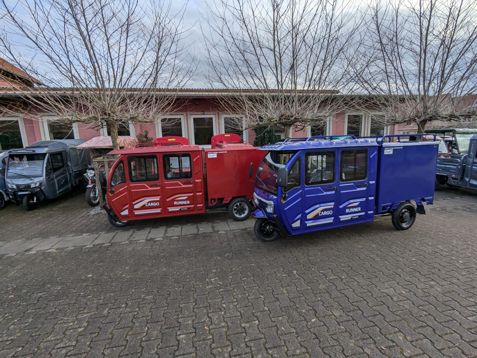 Modellübersicht Doppelkabiner in Rot und Blau, parkend auf einem Innenhof