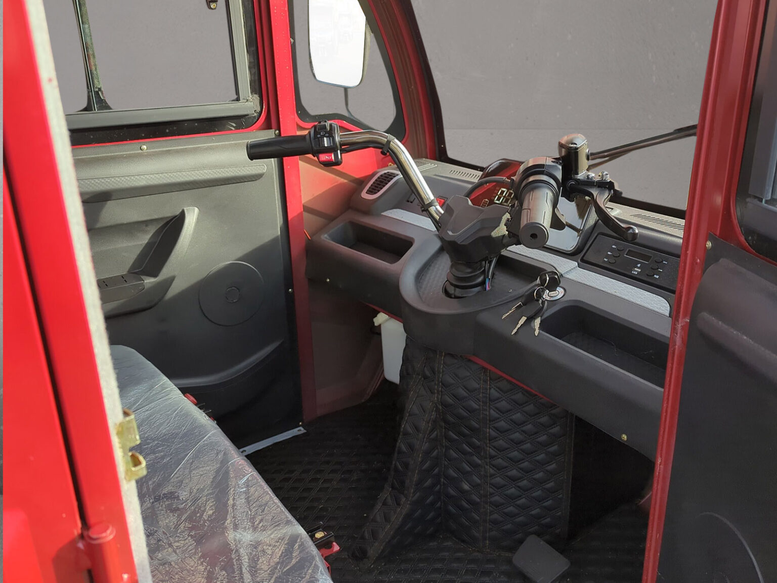 Innenraumansicht mit Lenkrad, Schalthebel und Fahrerbereich im roten Doppelkabiner