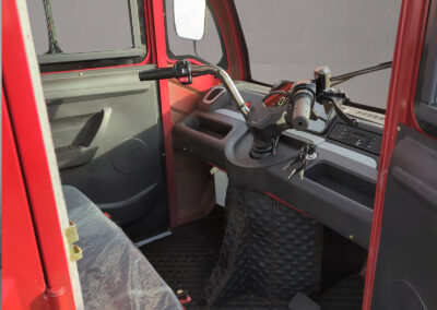Innenraumansicht mit Lenkrad, Schalthebel und Fahrerbereich im roten Doppelkabiner