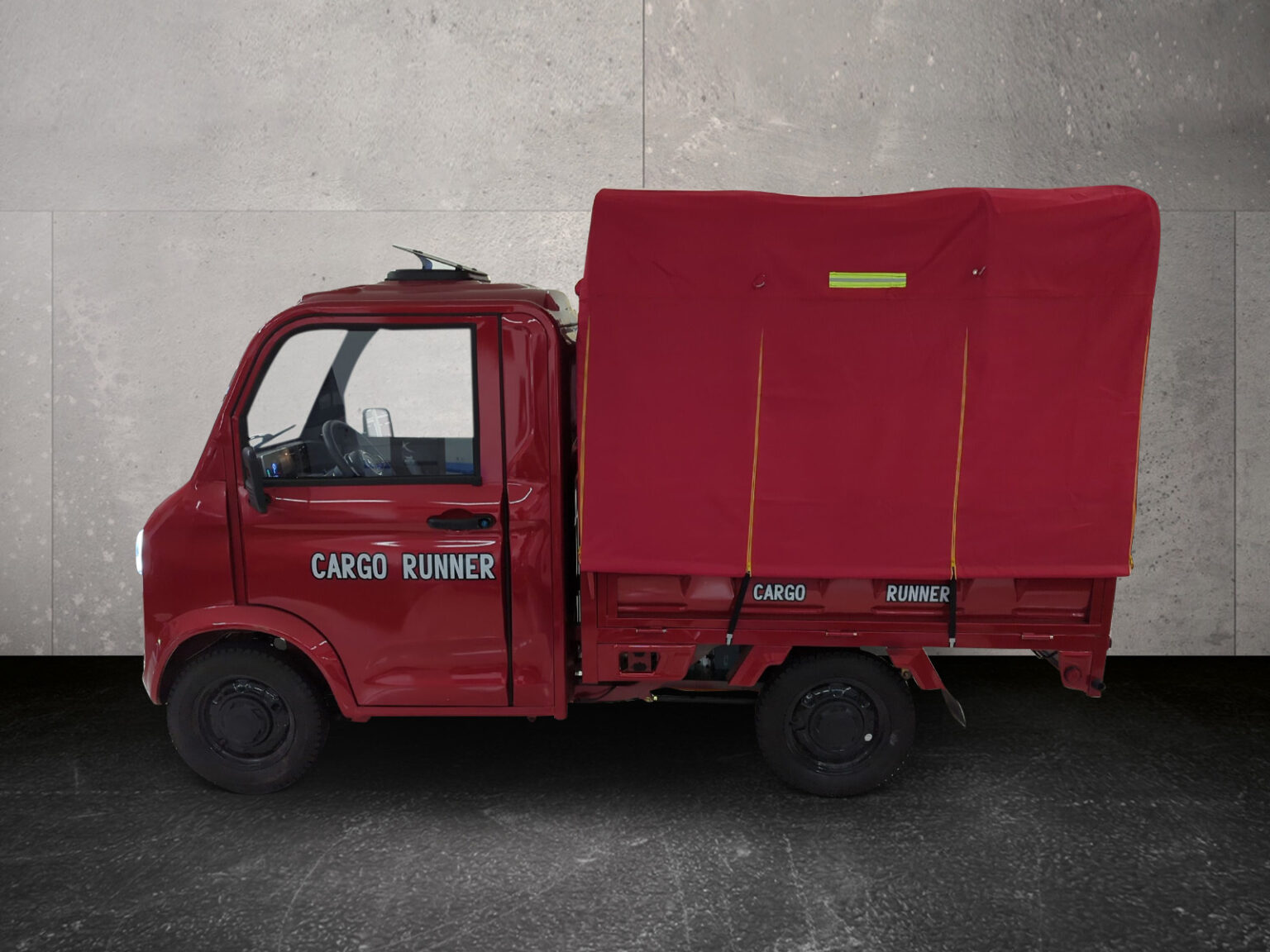 Seitenansicht des Cargo Runner Toro in Rot mit Kipppritsche auf grauem Hintergrund