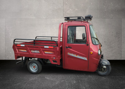 Seitenansicht Voltina in Rot mit gekippter Ladefläche, fotografiert von links